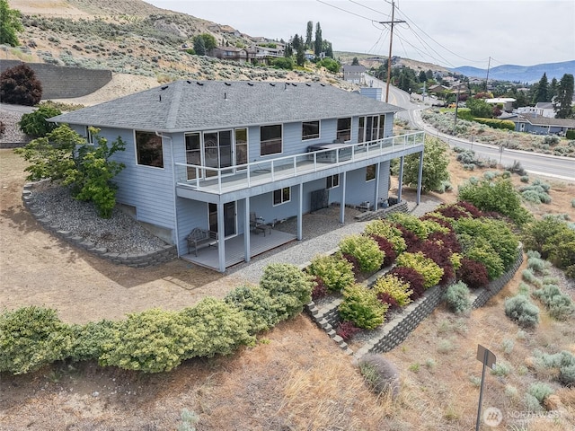 582 Lower Daniels Dr, East Wenatchee, WA 98802 - back of property featuring a deck with mountain view, a shingled roof, and a patio area