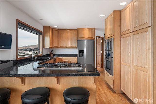 582 Lower Daniels Dr, East Wenatchee, WA 98802 - kitchen with stainless steel appliances, a peninsula, a kitchen breakfast bar, recessed lighting, and light wood-type flooring