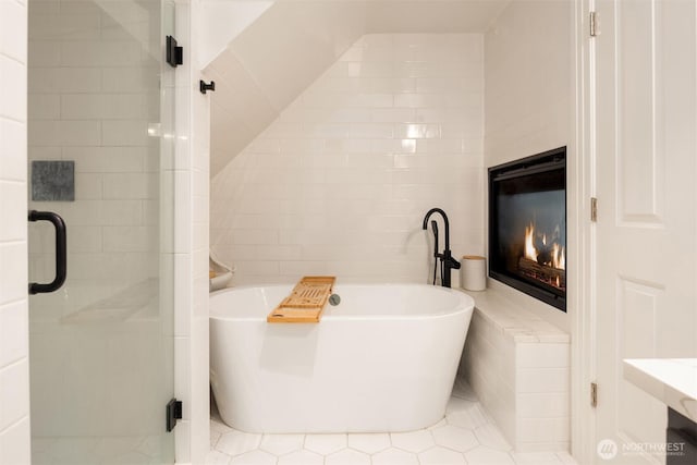1012 2nd Ave W, Seattle, WA 98119 - full bathroom featuring a glass covered fireplace, a soaking tub, a stall shower, tile walls, and tile patterned flooring