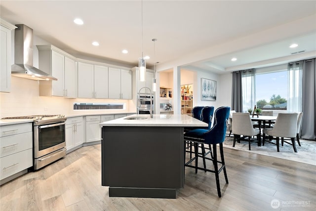 3359 Terry Ln, Enumclaw, WA 98022 - kitchen featuring stainless steel range, wall chimney exhaust hood, a kitchen island with sink, a kitchen bar, and light wood-type flooring