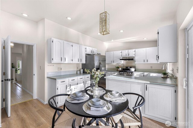 7969 W Golf Course Dr, Birch Bay, WA 98230 - kitchen featuring appliances with stainless steel finishes, under cabinet range hood, white cabinets, light wood-style flooring, and pendant lighting
