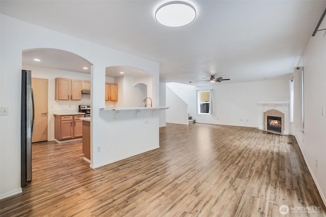14926 Woodland Ave E, Puyallup, WA 98375 - unfurnished living room featuring light wood-style flooring, a ceiling fan, a lit fireplace, stairs, and recessed lighting