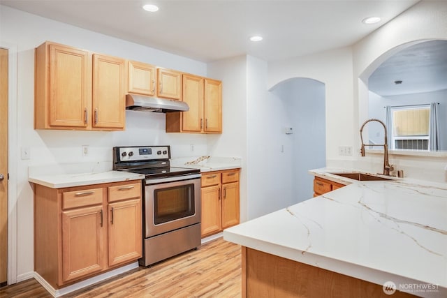 14926 Woodland Ave E, Puyallup, WA 98375 - kitchen with stainless steel electric range, under cabinet range hood, arched walkways, light stone countertops, and light wood finished floors