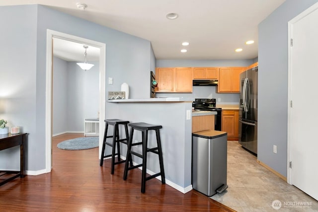 1736 E 39th St, Tacoma, WA 98404 - kitchen with black electric range, freestanding refrigerator, under cabinet range hood, a kitchen bar, and recessed lighting