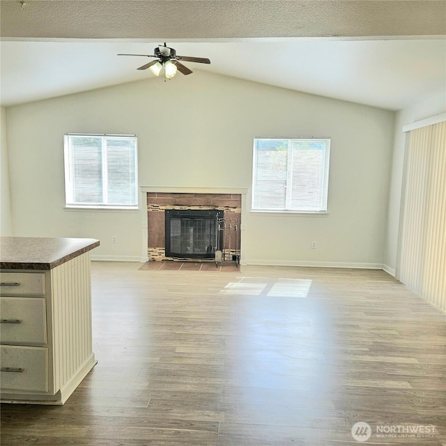 24827 36th Ave E, Spanaway, WA 98387 - unfurnished living room featuring healthy amount of natural light, wood finished floors, a ceiling fan, a fireplace with flush hearth, and lofted ceiling
