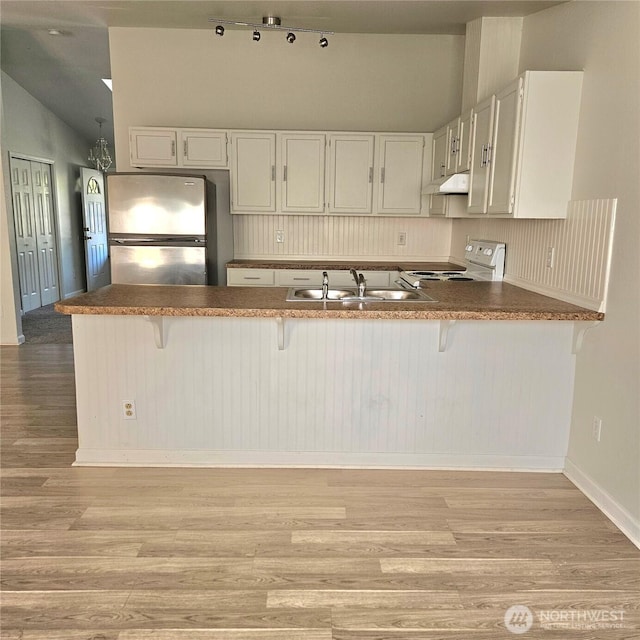 24827 36th Ave E, Spanaway, WA 98387 - kitchen with freestanding refrigerator, range, light wood finished floors, under cabinet range hood, and lofted ceiling