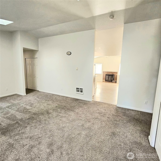 24827 36th Ave E, Spanaway, WA 98387 - carpeted spare room with a glass covered fireplace, a skylight, vaulted ceiling, and a smoke detector