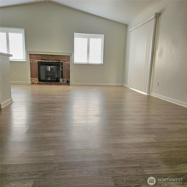 24827 36th Ave E, Spanaway, WA 98387 - unfurnished living room featuring vaulted ceiling, wood finished floors, and a glass covered fireplace