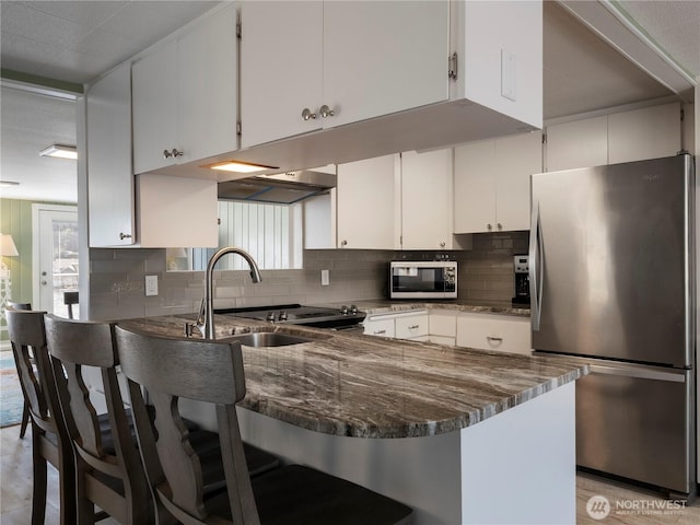 7217 20th Ave SE, Lacey, WA 98503 - kitchen with stainless steel appliances, a peninsula, tasteful backsplash, under cabinet range hood, and dark stone counters