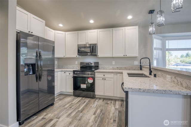 213 N Wynoochee Dr SW, Ocean Shores, WA 98569 - kitchen featuring stainless steel appliances, a sink, a peninsula, light wood-type flooring, and light stone countertops
