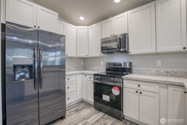 213 N Wynoochee Dr SW, Ocean Shores, WA 98569 - kitchen with stainless steel appliances, white cabinetry, light wood-style flooring, recessed lighting, and light stone countertops