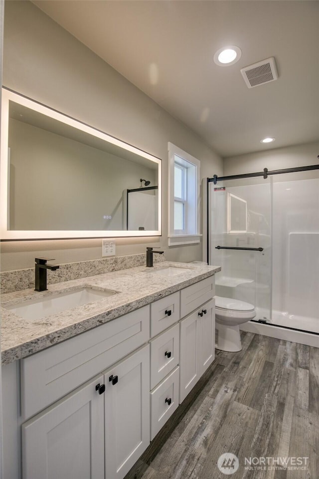 213 N Wynoochee Dr SW, Ocean Shores, WA 98569 - bathroom featuring double vanity, a stall shower, toilet, wood finished floors, and recessed lighting