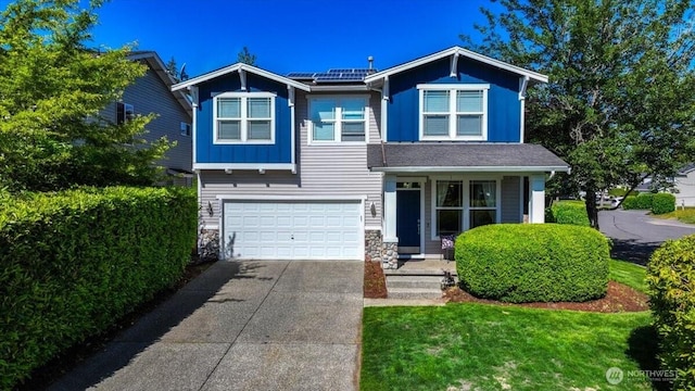 15204 48th Ave SE, Everett, WA 98208 - view of front facade featuring driveway, stone siding, roof mounted solar panels, and an attached garage