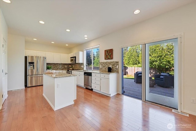 15204 48th Ave SE, Everett, WA 98208 - kitchen featuring stainless steel appliances, white cabinets, backsplash, light stone counters, and light wood-style floors