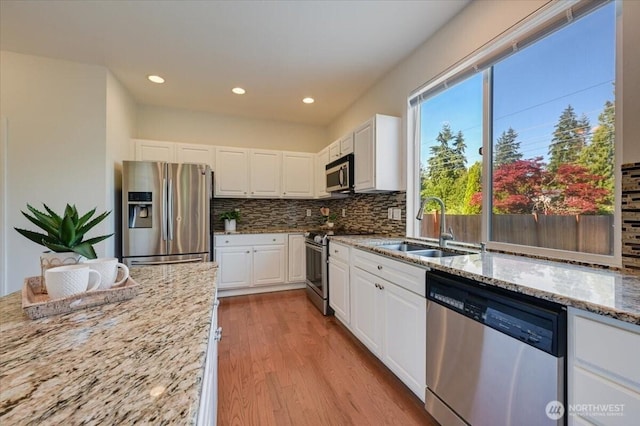 15204 48th Ave SE, Everett, WA 98208 - kitchen featuring appliances with stainless steel finishes, light stone counters, decorative backsplash, white cabinets, and light wood-style floors
