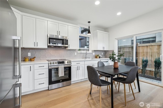 7741 15th Ave NE Unit C, Seattle, WA 98115 - kitchen with stainless steel appliances, a sink, light wood-type flooring, tasteful backsplash, and recessed lighting