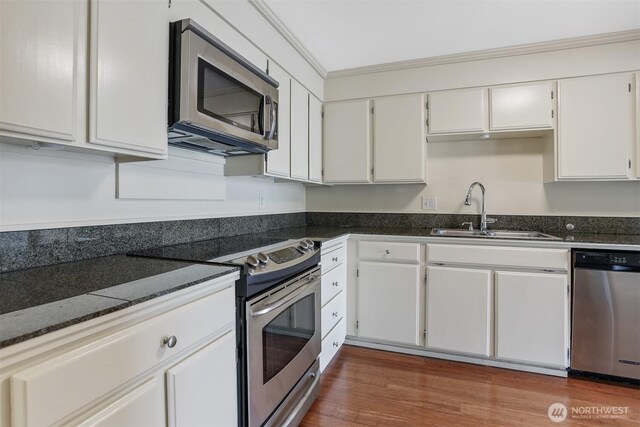 3717 Beach Dr SW Unit 113, Seattle, WA 98116 - kitchen featuring appliances with stainless steel finishes, white cabinets, wood finished floors, and ornamental molding
