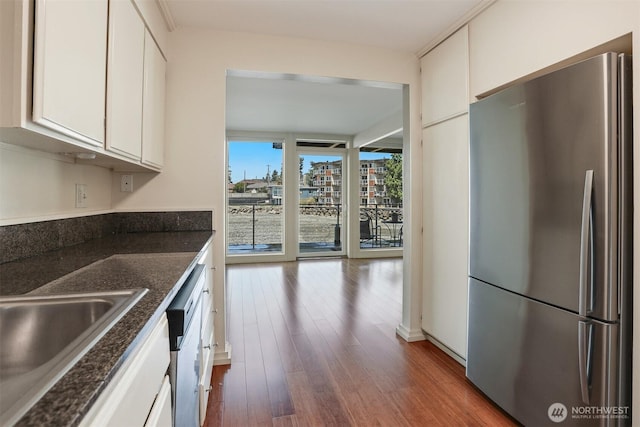 3717 Beach Dr SW Unit 113, Seattle, WA 98116 - kitchen with freestanding refrigerator, wood finished floors, dishwashing machine, white cabinetry, and dark stone counters