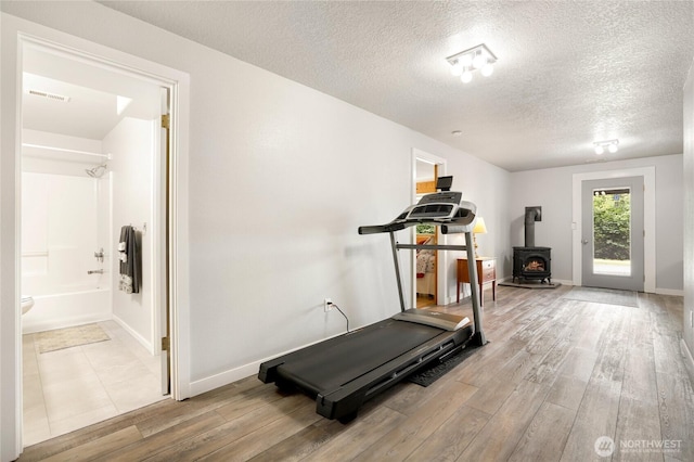 4004 Saje Ln, Sedro Woolley, WA 98284 - exercise room featuring a wood stove, wood finished floors, and a textured ceiling