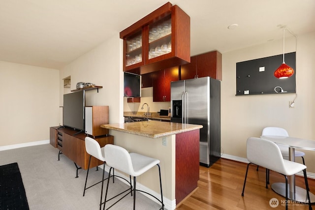 1105 Spring St Unit 1106, Seattle, WA 98104 - kitchen featuring stainless steel refrigerator with ice dispenser, a kitchen breakfast bar, a peninsula, glass insert cabinets, and light wood finished floors
