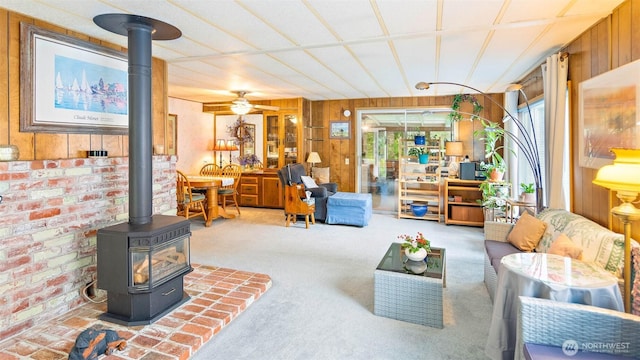 20 NE Wanda Ct, Belfair, WA 98528 - carpeted living area with a wood stove, wood walls, and a ceiling fan