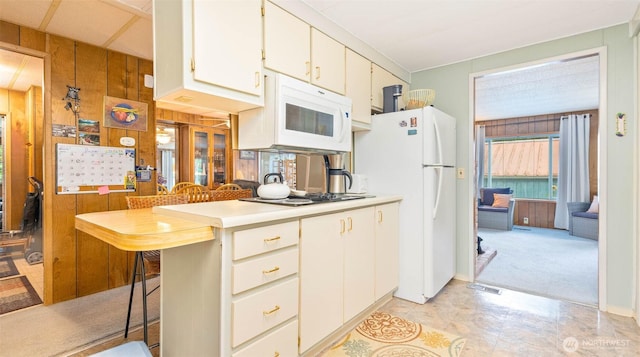 20 NE Wanda Ct, Belfair, WA 98528 - kitchen featuring white appliances, wooden walls, light countertops, white cabinetry, and a breakfast bar