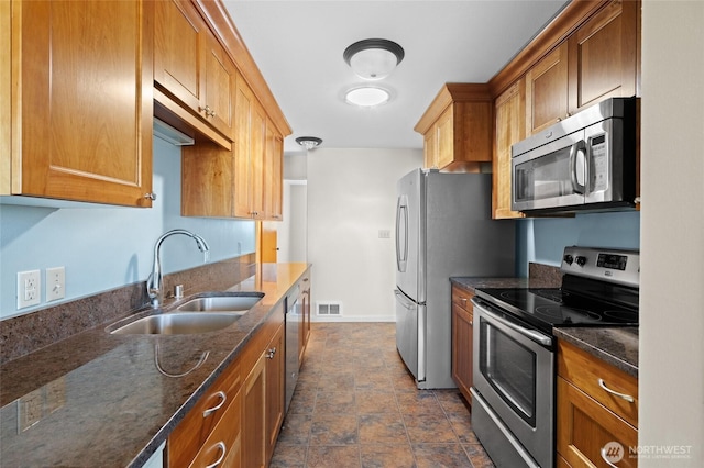 2834 Leeward Way, Bellingham, WA 98226 - kitchen featuring appliances with stainless steel finishes, stone finish flooring, dark stone counters, and brown cabinetry