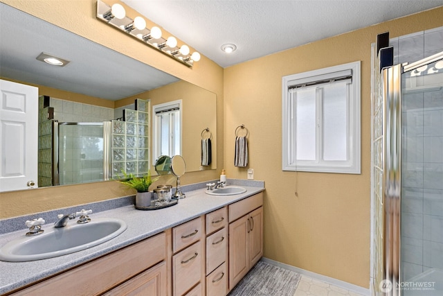 22023 11th Ave S, Des Moines, WA 98198 - bathroom featuring a stall shower, double vanity, healthy amount of natural light, and a textured ceiling