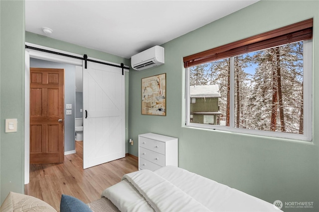 11358 River Bend Dr, Leavenworth, WA 98826 - bedroom featuring an AC wall unit, light wood finished floors, and a barn door