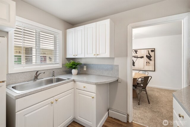 6017 Fauntleroy Way SW, Seattle, WA 98136 - kitchen featuring a baseboard radiator, white cabinets, light countertops, and freestanding refrigerator