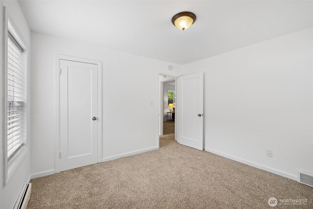 6017 Fauntleroy Way SW, Seattle, WA 98136 - unfurnished bedroom featuring a baseboard heating unit, light carpet, and multiple windows