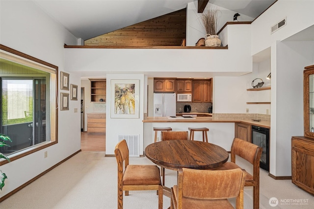 225 NE 19th St Unit 24, East Wenatchee, WA 98802 - dining space featuring wine cooler, high vaulted ceiling, and light colored carpet