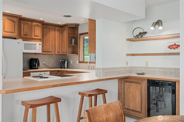 225 NE 19th St Unit 24, East Wenatchee, WA 98802 - kitchen with open shelves, white appliances, a kitchen bar, a peninsula, and backsplash