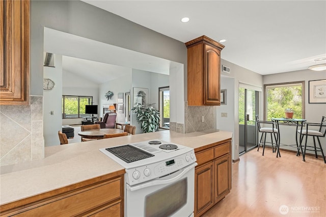 225 NE 19th St Unit 24, East Wenatchee, WA 98802 - kitchen featuring white electric range oven, brown cabinetry, light countertops, backsplash, and recessed lighting