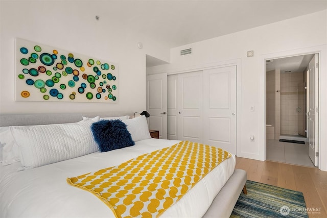 1920 4th Ave Unit 604, Seattle, WA 98101 - bedroom with wood finished floors, a closet, and connected bathroom