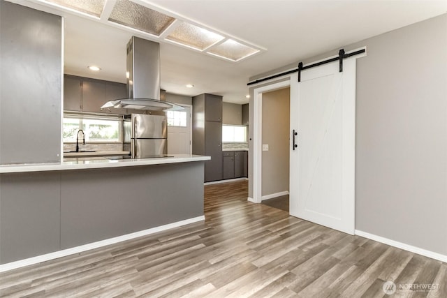 32206 27th Ave SW, Federal Way, WA 98032 - kitchen with freestanding refrigerator, island exhaust hood, a barn door, gray cabinetry, and wood finished floors