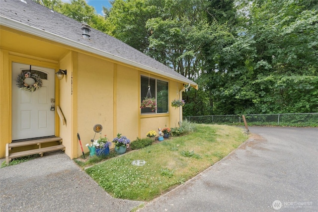 12912 62nd Ave NW Unit B5, Gig Harbor, WA 98332 - view of exterior entry featuring stucco siding, roof with shingles, and view of scattered trees