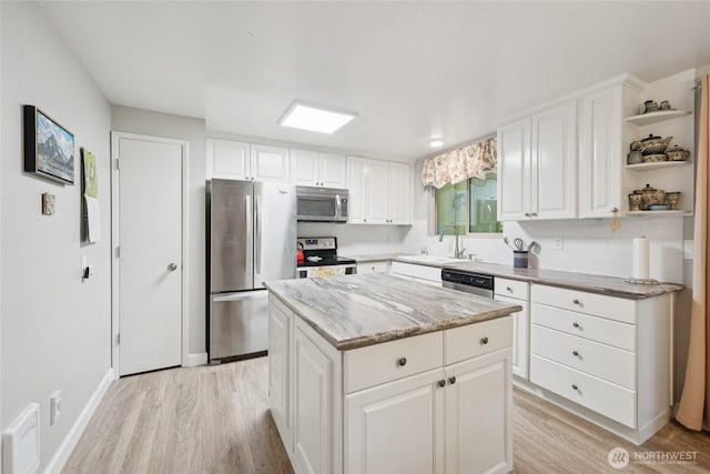 12912 62nd Ave NW Unit B5, Gig Harbor, WA 98332 - kitchen with appliances with stainless steel finishes, light wood finished floors, open shelves, a kitchen island, and white cabinetry