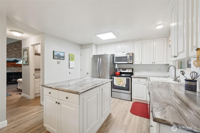 12912 62nd Ave NW Unit B5, Gig Harbor, WA 98332 - kitchen featuring appliances with stainless steel finishes, light wood-style floors, a kitchen island, white cabinetry, and light stone countertops