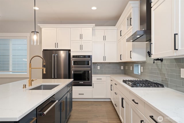7585 S 130th Pl, Seattle, WA 98178 - kitchen featuring wall chimney exhaust hood, appliances with stainless steel finishes, white cabinetry, decorative backsplash, and hanging light fixtures