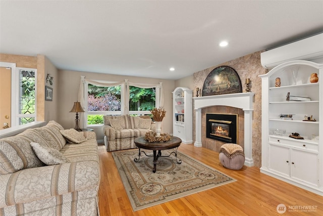 6600 Klein St NW, Olympia, WA 98502 - living room with a wall unit AC, wood finished floors, a tiled fireplace, and recessed lighting