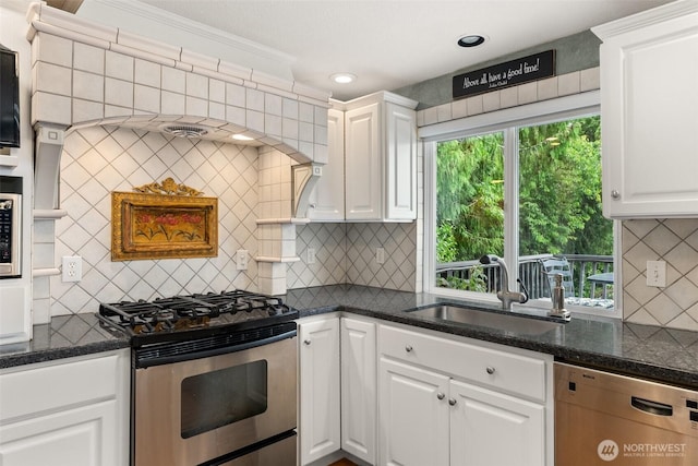 6600 Klein St NW, Olympia, WA 98502 - kitchen featuring appliances with stainless steel finishes, decorative backsplash, white cabinetry, crown molding, and dark stone countertops