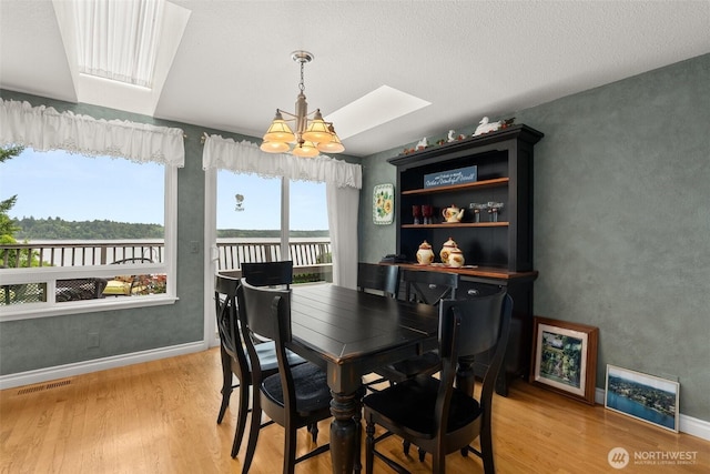 6600 Klein St NW, Olympia, WA 98502 - dining room featuring a skylight, a chandelier, light wood-type flooring, and a water view