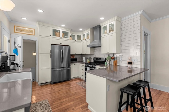 206 S Miller St, Wenatchee, WA 98801 - kitchen with appliances with stainless steel finishes, wall chimney exhaust hood, crown molding, a peninsula, and decorative backsplash
