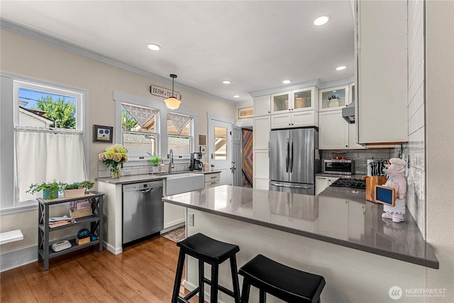 206 S Miller St, Wenatchee, WA 98801 - kitchen with stainless steel appliances, a sink, a peninsula, white cabinetry, and ornamental molding