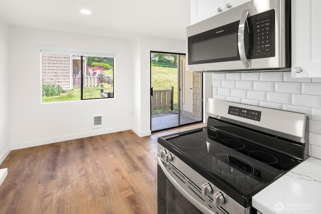 2020 Grant Ave S Unit B103, Renton, WA 98055 - kitchen featuring stainless steel appliances, baseboards, white cabinets, wood finished floors, and backsplash