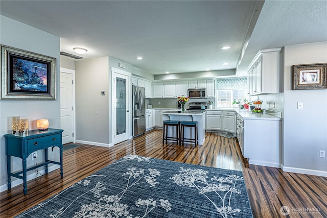 17716 25th Ave E, Tacoma, WA 98445 - kitchen featuring stainless steel appliances, a kitchen island, dark wood-style floors, white cabinetry, and light countertops