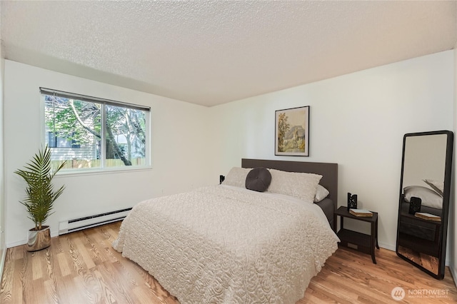 921 130th St SW Unit E102, Everett, WA 98204 - bedroom with a baseboard radiator, light wood-type flooring, and a textured ceiling