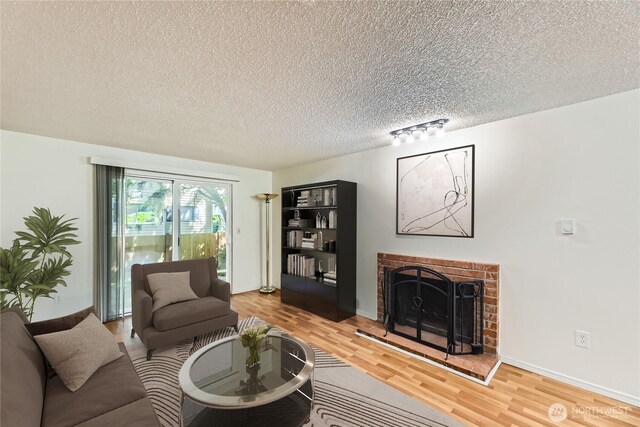 921 130th St SW Unit E102, Everett, WA 98204 - living room with light wood-type flooring, a textured ceiling, a fireplace, and rail lighting