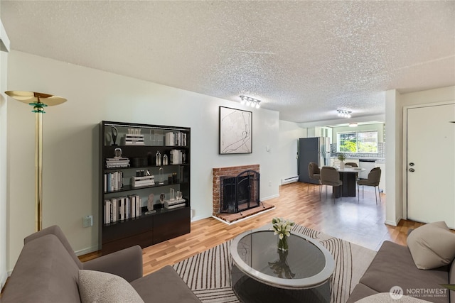 921 130th St SW Unit E102, Everett, WA 98204 - living area with light wood-type flooring, a textured ceiling, a brick fireplace, and a baseboard radiator